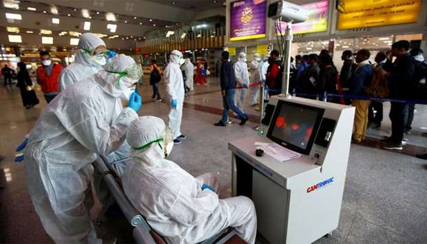 Medical staff in protective gear look at a screen while checking temperatures of passengers upon their arrival, following an outbreak of the coronavirus, at Najaf airport, in the holy city of Najaf, Iraq
