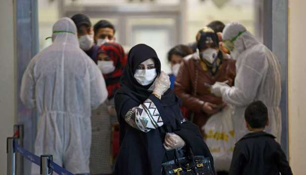 Medical staff in protective gears distribute information sheets to Iraqi passengers returning from Iran at Najaf International Airport yesterday