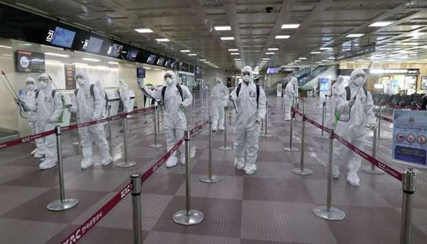 South Korean soldiers wearing protective gear spray disinfectant to help prevent the spread of the COVID-19 coronavirus, at the Daegu International Airport in Daegu