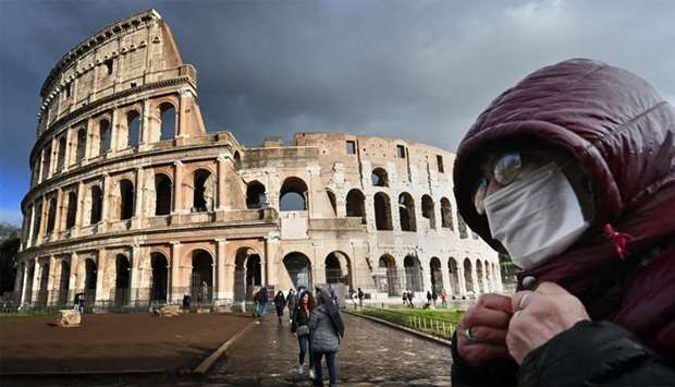 A man wearing a protective mask passes by the Coliseum in Rome amid fear of Covid-19 epidemic