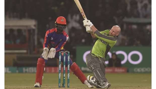Lahore Qalandarsu2019 Ben Dunk (R) hits a shot as Karachi Kingsu2019 wicketkeeper Chadwick  Walton looks on in Lahore.