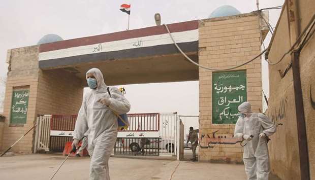 Workers in protective suits spray disinfectants near the gate of Shalamcha Border Crossing, after Iraq shut a border crossing to travellers between Iraq and Iran, yesterday.