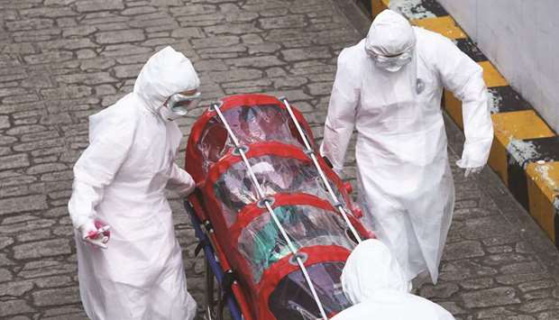 Medical staff members wearing protective gear carry a patient infected with the Covid-19 coronavirus at a hospital in Seoul yesterday.