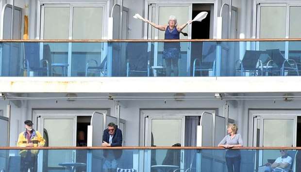 A woman gestures as other people look on from aboard the Grand Princess cruise ship, operated by Princess Cruises, as it maintains a holding pattern about 25 miles off the coast of San Francisco, California
