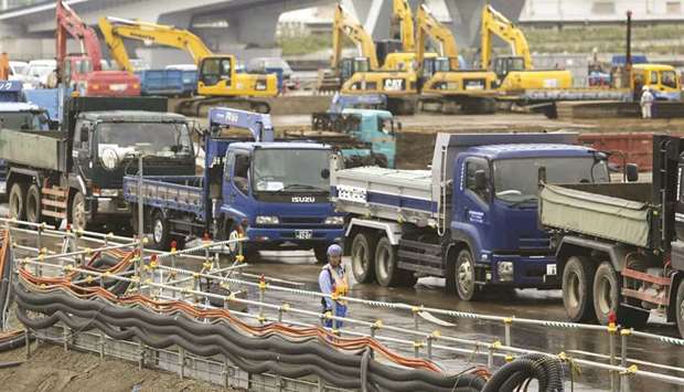 A man stands next to trucks as he controls the traffic at a construction site in Tokyo. Japanu2019s economy shrank an annualised 7.1% in the three months through December, revised data showed yesterday, more than a preliminary reading of 6.3% and a median market forecast of 6.6%.