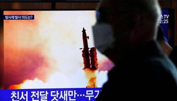 A man walks past a TV broadcasting file footage for a news report on North Korea firing an unidentified projectile, in Seoul