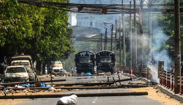 Military trucks are seen near a burning barricade, erected by protesters then set on fire by soldiers, during a crackdown on demonstrations against the military coup in Yangon