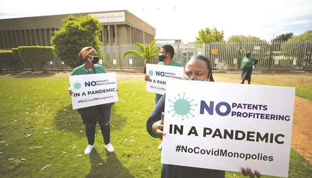 Demonstrators hold placards during a protest yesterday against coronavirus disease (Covid-19) vaccination distribution inequality, outside the Johnson and Johnson offices in Cape Town.