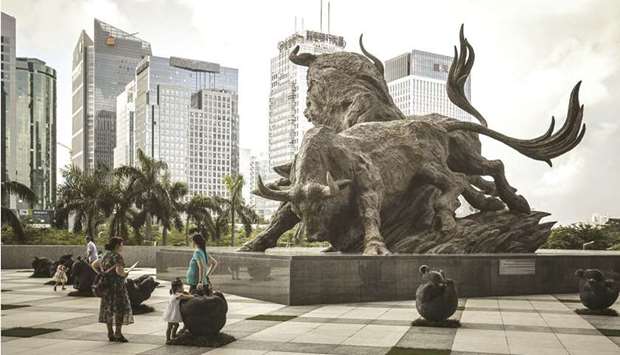 People stand in front of a sculpture of bulls at the entrance to the Shenzhen Stock Exchange building. Chinau2019s policymakers, spurred to act by ballooning debt, are trying to get the countryu2019s $10.7tn stock market to play a larger role in funding the economy.
