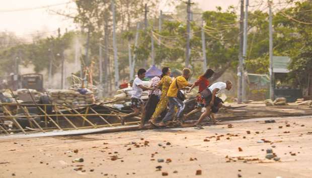 People run past makeshift barricades set up by protesters, during a crackdown by security forces on demonstrations against the military coup, in Yangonu2019s Hlaing Tharyar township.