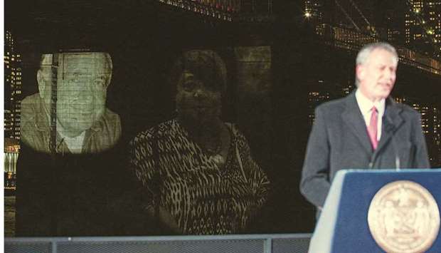New York Mayor de Blasio speaks as images of Covid-19 victims are projected over the Brooklyn bridge.