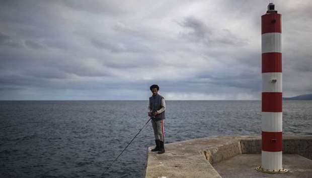An angler holds his fishing rod on Corvo Island's pier in Azores on March 10