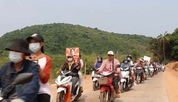 Protesters hold pictures of Aung San Suu Kyi as they ride their motorcycles in Dawei district, Myanmar