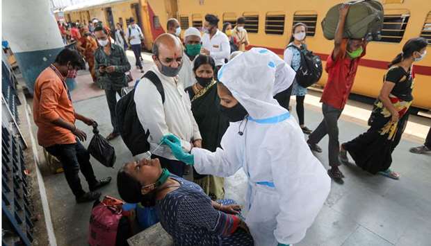 A health worker in personal protective equipment (PPE) collects a swab sample from a woman during a rapid antigen testing campaign for the coronavirus disease (Covid-19), at a railway station platform in Mumbai, India