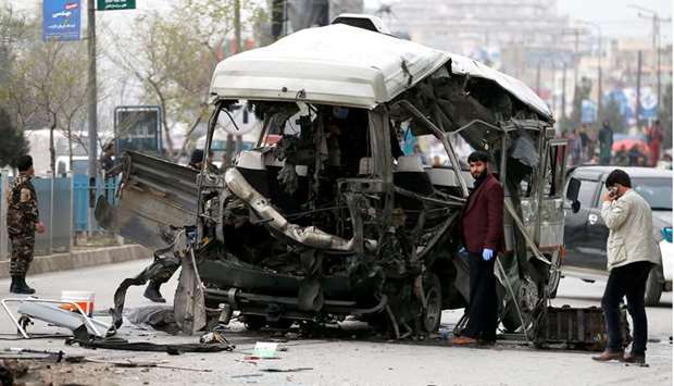 Afghan officials inspect a damaged minibus after a blast in Kabul, Afghanistan
