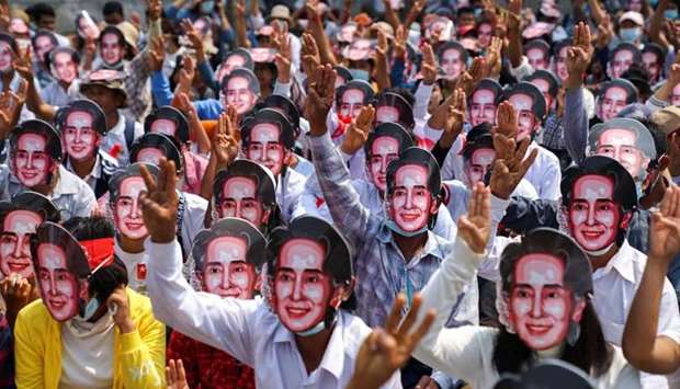Protesters wearing masks depicting ousted leader Aung San Suu Kyi, flash three-finger salutes as they take part in a protest against the military coup in Yangon yesterday.