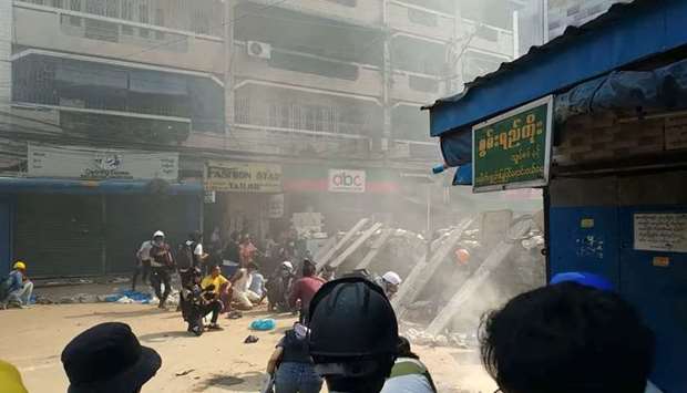 Protesters cover behind a makeshift barricade facing police in Hlaing Township, Yangon