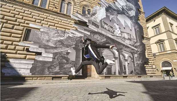 French artist JR jumps as he poses during the unveiling of his visual installation La Ferita (The Wound) on the facade of the Renaissance Palazzo Strozzi in Florence.