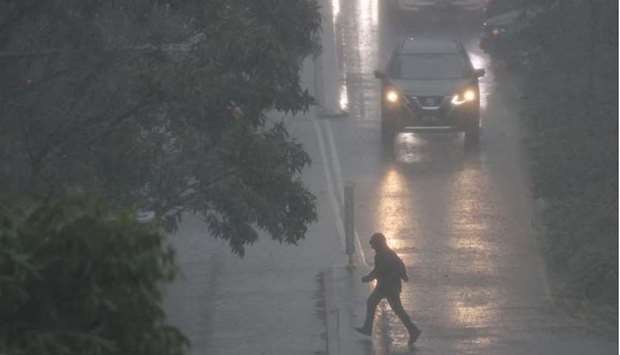 A person crosses a street in severe rain as the state of New South Wales experiences widespread flooding, in Sydney, Australia
