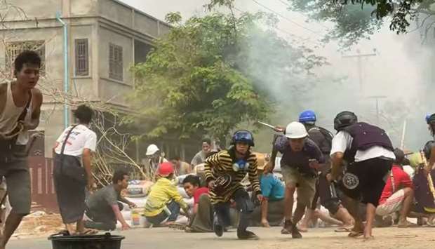 Protesters take cover during clashes with security forces in Monywa, Myanmar, in this still image from a video obtained by Reuters