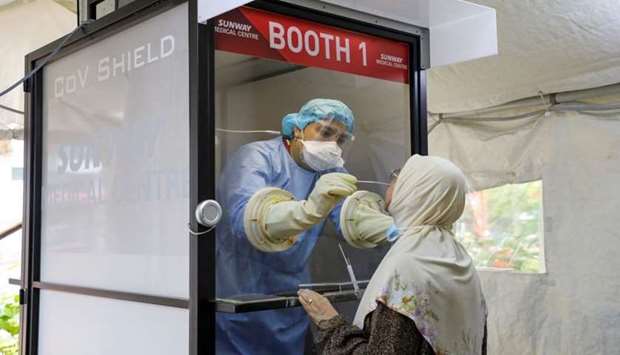 A Medical worker collects a swab sample from a woman to be tested for the coronavirus disease at Sunway Medical Centre, in Subang Jaya, Malaysia on March 12