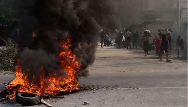 Protesters carrying sandbags to erect makeshift barricades, while a barricade of tyres burns, during a crackdown by security forces on demonstrations against the military coup in Mandalay.