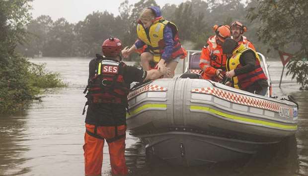 A family rescued by a State Emergency Service crew makes it to safety after being trapped by rising floodwaters, as the state of New South Wales experiences widespread flooding and severe weather, in the suburb of Sackville North in Sydney, yesterday.