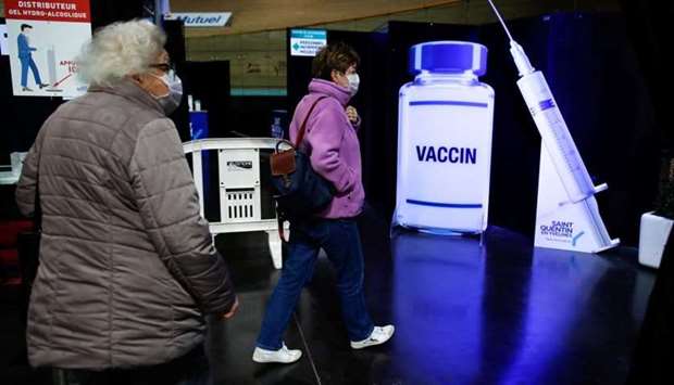 Women leave after getting a dose of the ,Comirnaty, Pfizer-BioNTech Covid-19 vaccine as part of the coronavirus disease vaccination campaign at the indoor Velodrome National of Saint-Quentin-en-Yvelines in Montigny-le-Bretonneux, southwest of Paris, France
