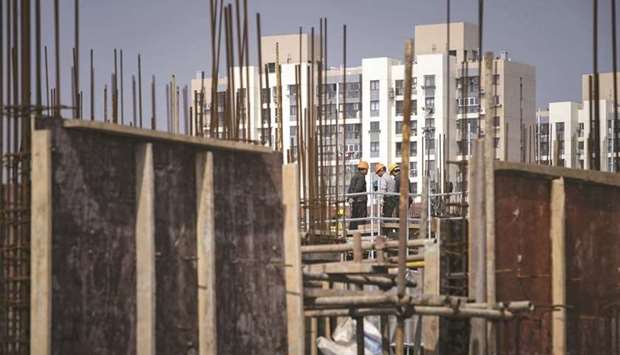 Workers stand on a scaffolding at a construction site for a residential development on the outskirts