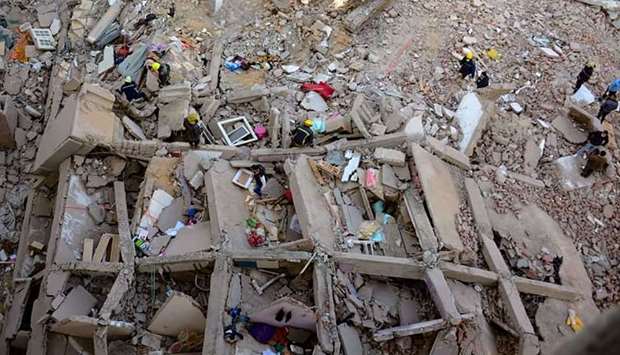 People and rescuers gather around the rubble of a building that collapsed in the Egyptian capital Ca