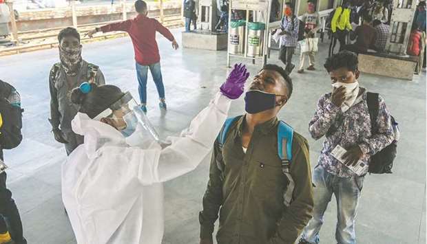 A health worker takes a swab sample for a Rapid Antigen Testing (RAT) from passengers arriving into Mumbai city at a railway terminus as made mandatory by the state government due to a rise in Covid-19 cases.