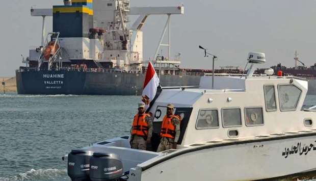 Egyptian coast guards patrol as a ship navigates the Suez Canal yesterday, a day after cargo vessel Ever Given was dislodged from its banks