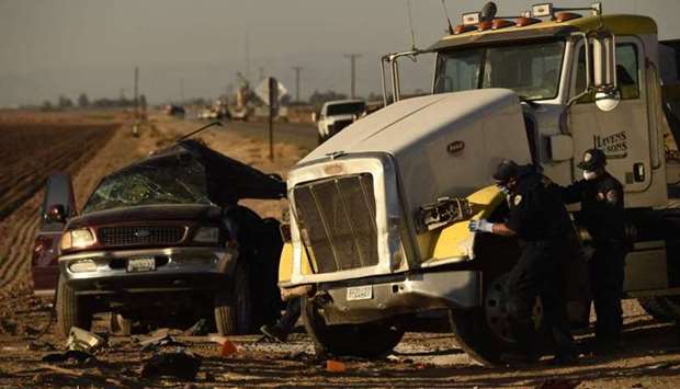 Investigators look over the scene of a crash between an SUV and a semi-truck full of gravel near Holtville, California.