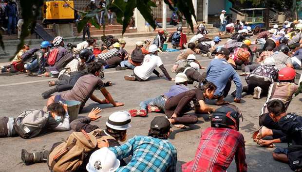 Protesters lie on the ground after police open fire to disperse an anti-coup protest in Mandalay, My