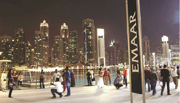 People have their pictures taken near an Emaar sign outside the Dubai Mall (file).  Emaar Properties, which built the cityu2019s iconic Burj Khlaifa tower, announced on Tuesday it plans to buy back a 15% stake in its Emaar Malls unit at a 36% discount to the 2.9 dirhams a share at which it sold it in 2014.