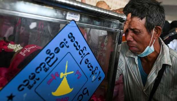 A man reacts in front of a casket with a body of a victim who was shot dead during the anti-coup protest, in a cemetery at the outskirts of Yangon, Myanmar