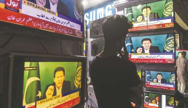 A shopkeeper in Karachi listens to Prime Minister Khan addressing the nation on television, after Foreign Minister Shah Mahmood Qureshi announced that Khan would seek a confidence vote in the National Assembly tomorrow.