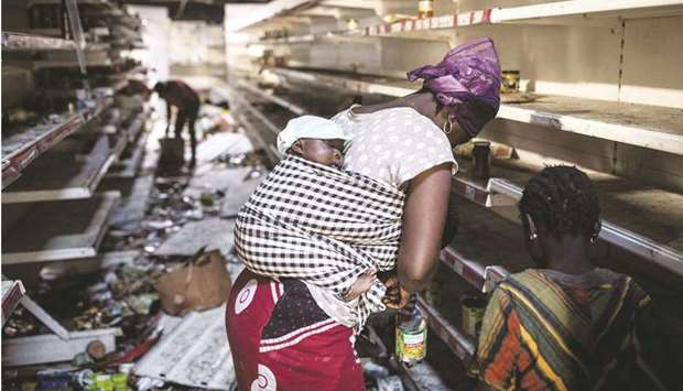 A woman collects groceries from a burnt down and looted Auchan supermarket in the up-market area of Almadies in Dakar yesterday.