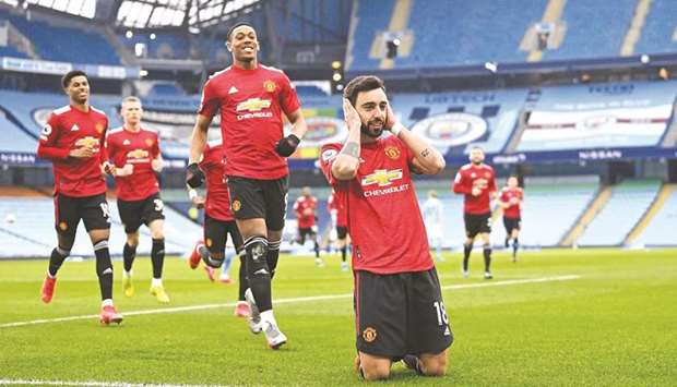 Manchester Unitedu2019s Portuguese midfielder Bruno Fernandes (R) celebrates with teammates after scoring from the penalty spot against Manchester City at the Etihad Stadium in Manchester yesterday.