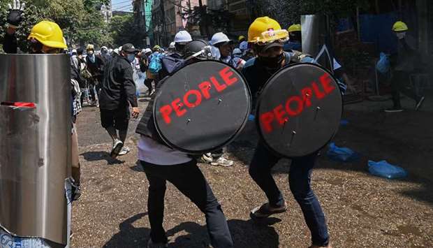 Protesters hold shields with the word u2018PEOPLEu2019 written on them during a demonstration in Yangon yesterday against the military coup.