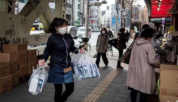 A vendor replenishes her stall with boxes of face masks in Tokyo