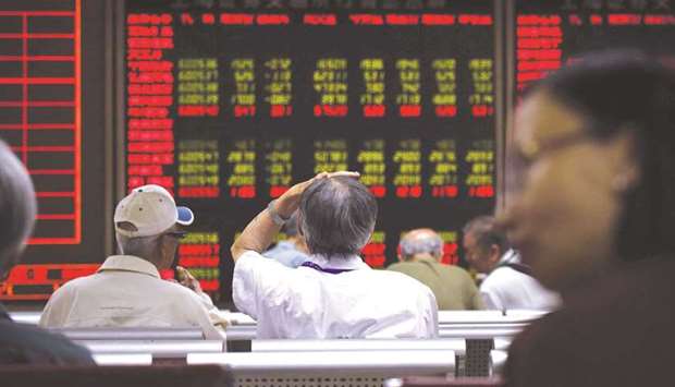 Investors look at screens showing stock market movements at a securities company in Beijing. The Composite index closed down 2.3% to 3,421.41 points yesterday.