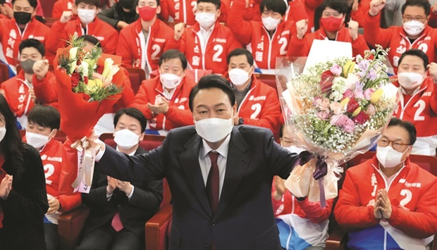 Yoon Suk-yeol holds bouquets as he is congratulated by partyu2019s members and lawmakers at the National Assembly in Seoul yesterday. (Reuters)