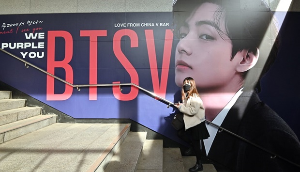 A woman walks past a big photo of V, a member of K-pop group BTS, at a subway station near Jamsil Olympic Stadium in Seoul on March 10, 2022, ahead of the group's live concert at the stadium.
