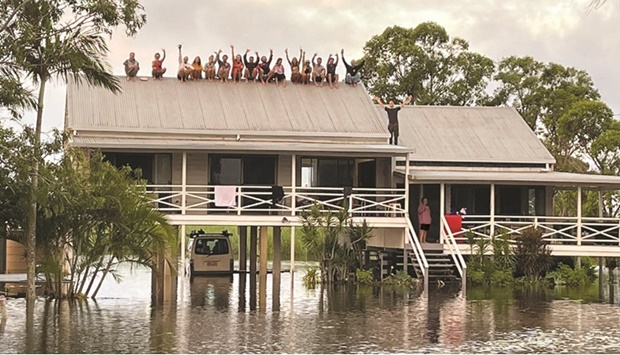 People wait to be rescued on the roof of a house along a flooded street in the Sunshine Coast region in Queensland, Australia.