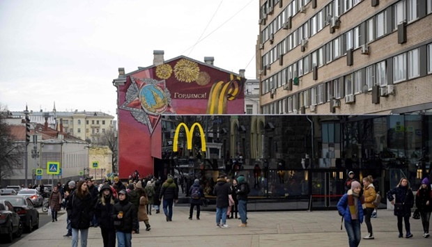People walk in front of the McDonald's flagship restaurant at Pushkinskaya Square - the first one of the chain opened in the USSR on January 31, 1990 - in central Moscow on March 13, 2022, McDonald's last day in Russia. AFP