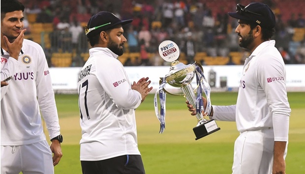 Indiau2019s Rohit Sharma (right) holds the trophy as his teammate Rishabh Pant watches at the end of the second Test against Sri Lanka at the M. Chinnaswamy Stadium in Bangalore yesterday. (AFP)