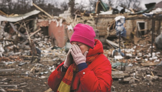 Irina Moprezova, 54, reacts in front of a house that was damaged in an aerial bombing in the city of Irpin, northwest of Kyiv on Sunday. (AFP)
