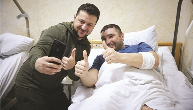 In this handout picture released and taken by Ukrainian Presidency Press Office, Ukrainian President Volodymyr Zelensky (left) snaps a selfie with an injured man laying on a bed during a visit at a military hospital following fightings in the Kyiv region. (AFP)