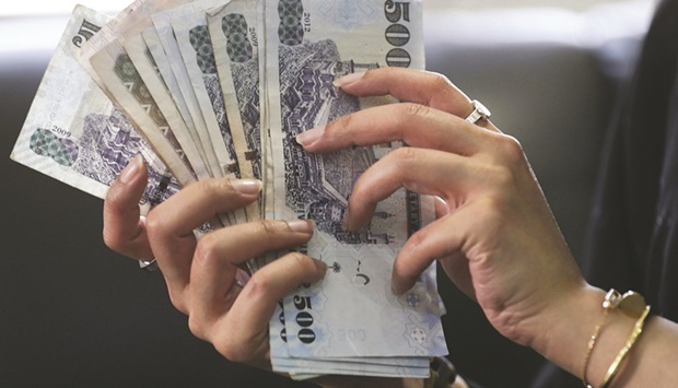 A Saudi woman counts Saudi riyal banknotes at a money exchange shop in Riyadh (file). Policymakers in Gulf countries including Saudi Arabia tend to match the Fedu2019s decisions to protect their currenciesu2019 pegs to the US dollar.